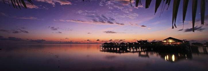 Water chalets of Sipadan Water Village reflected in calm water at dusk