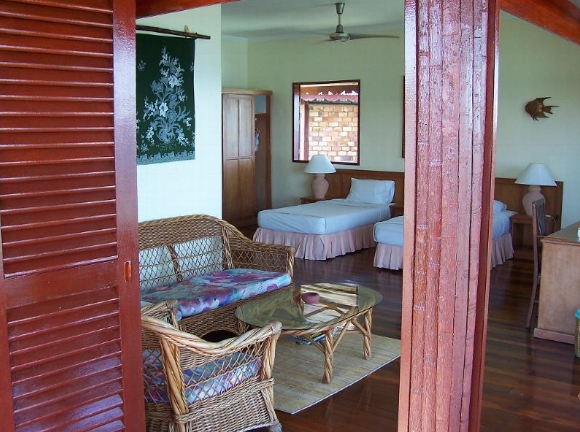 Timber interior of a water chalet at Sipadan Water Village with woven seating and beds